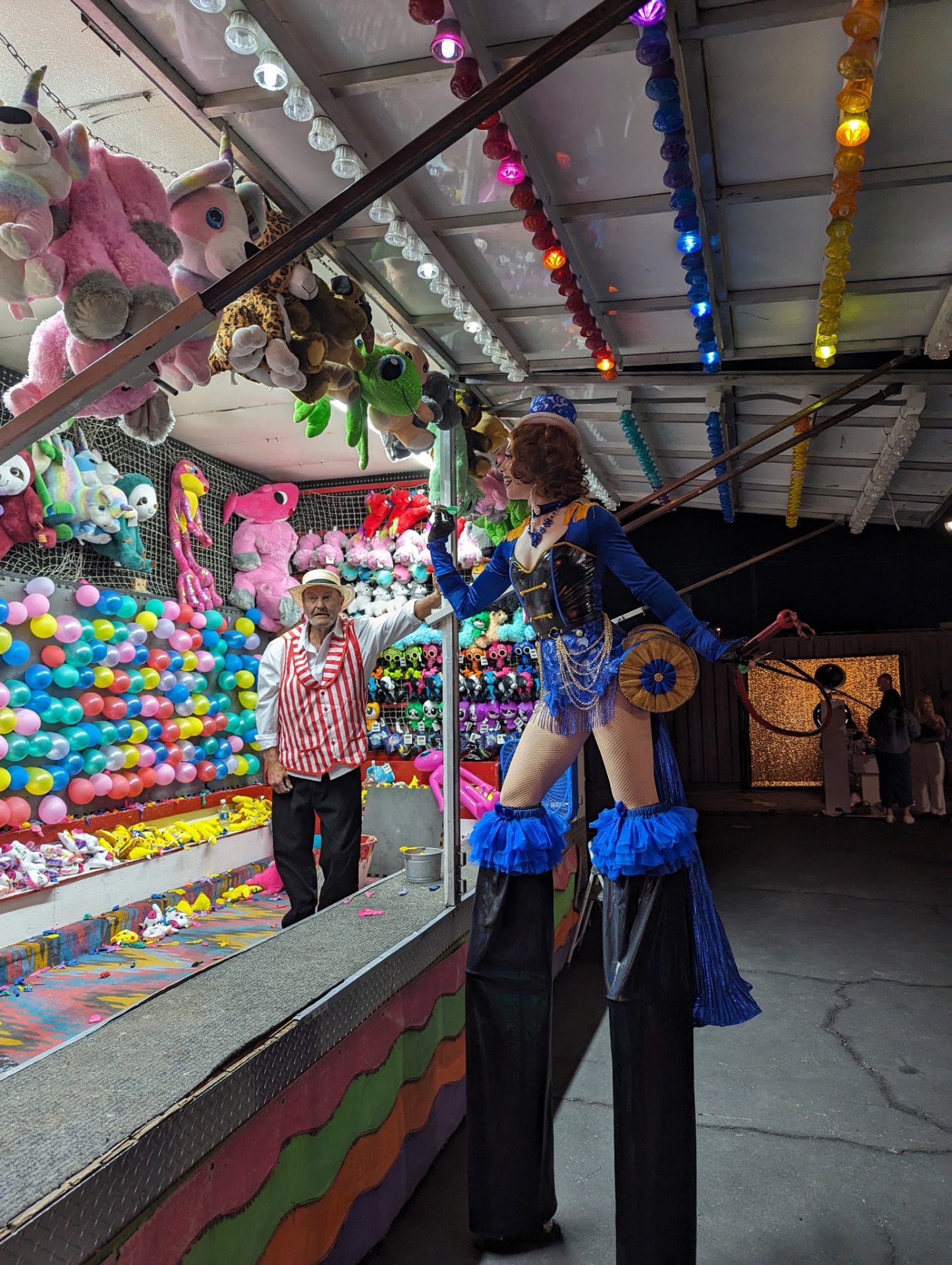 Carnival darts and balloon game booth with numbered scoreboard and bright lights