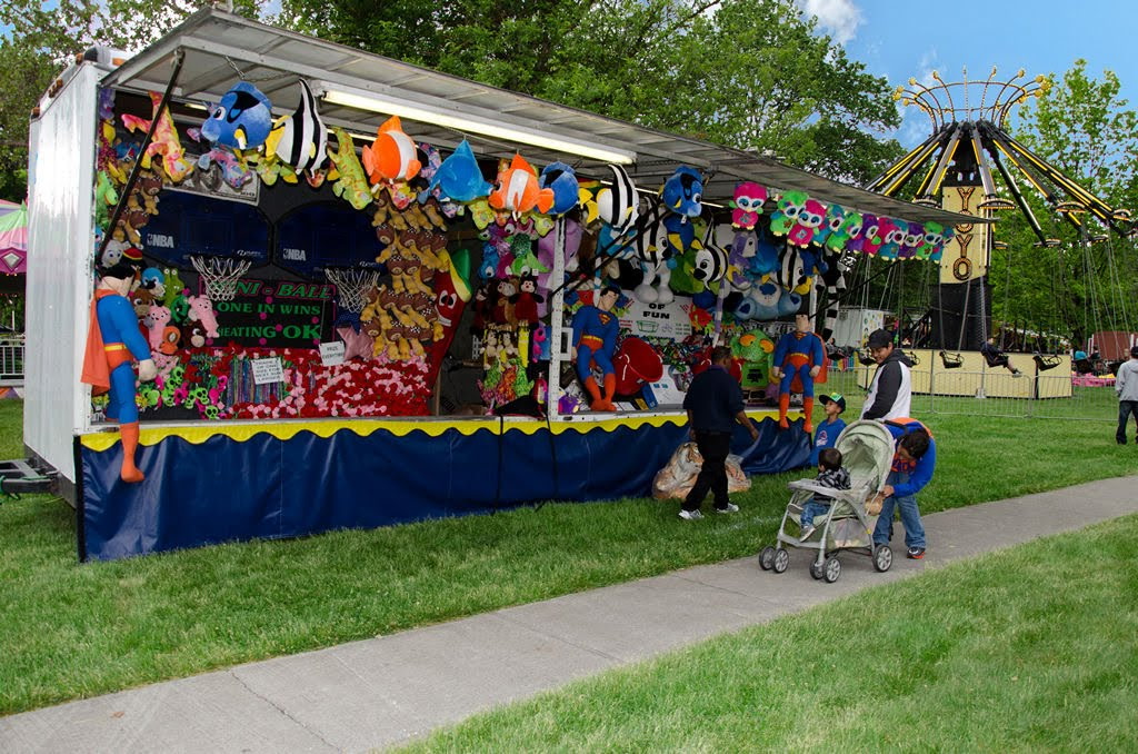 Carnival mini basketball game booth with NBA hoops, Superman plush, and a canopy of colorful plush prizes