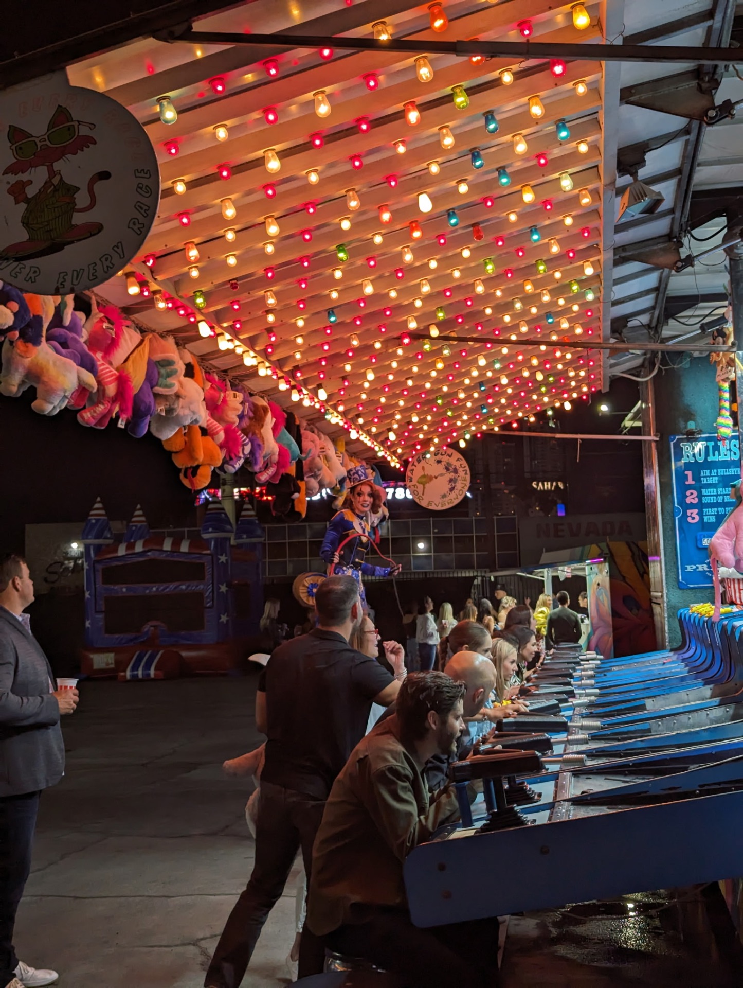 Bright blue Water Gun Race carnival game booth lined with stools and target boards