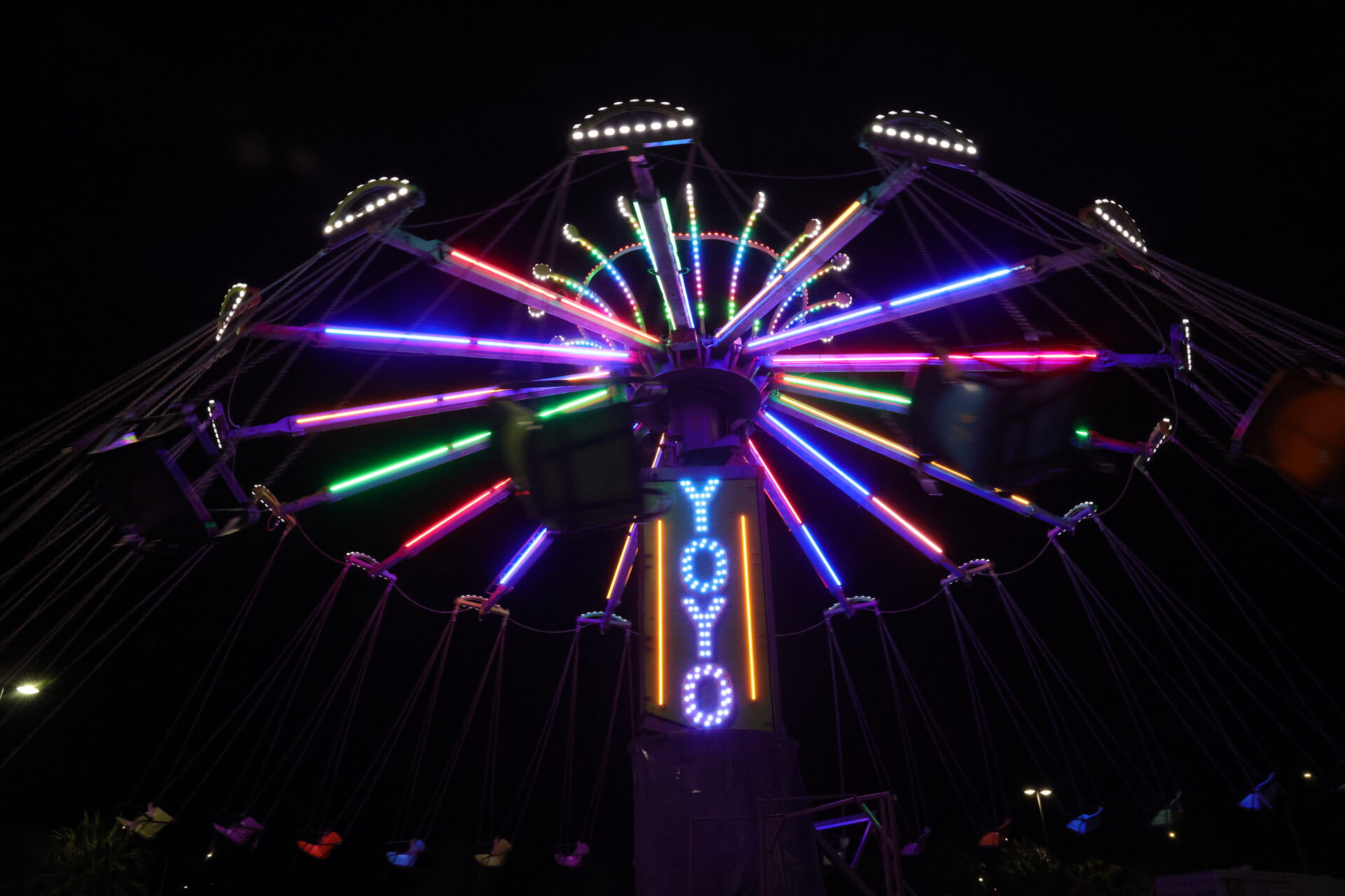 Chance Rides Yo-Yo swing ride with illuminated chairs spinning around the tower at night